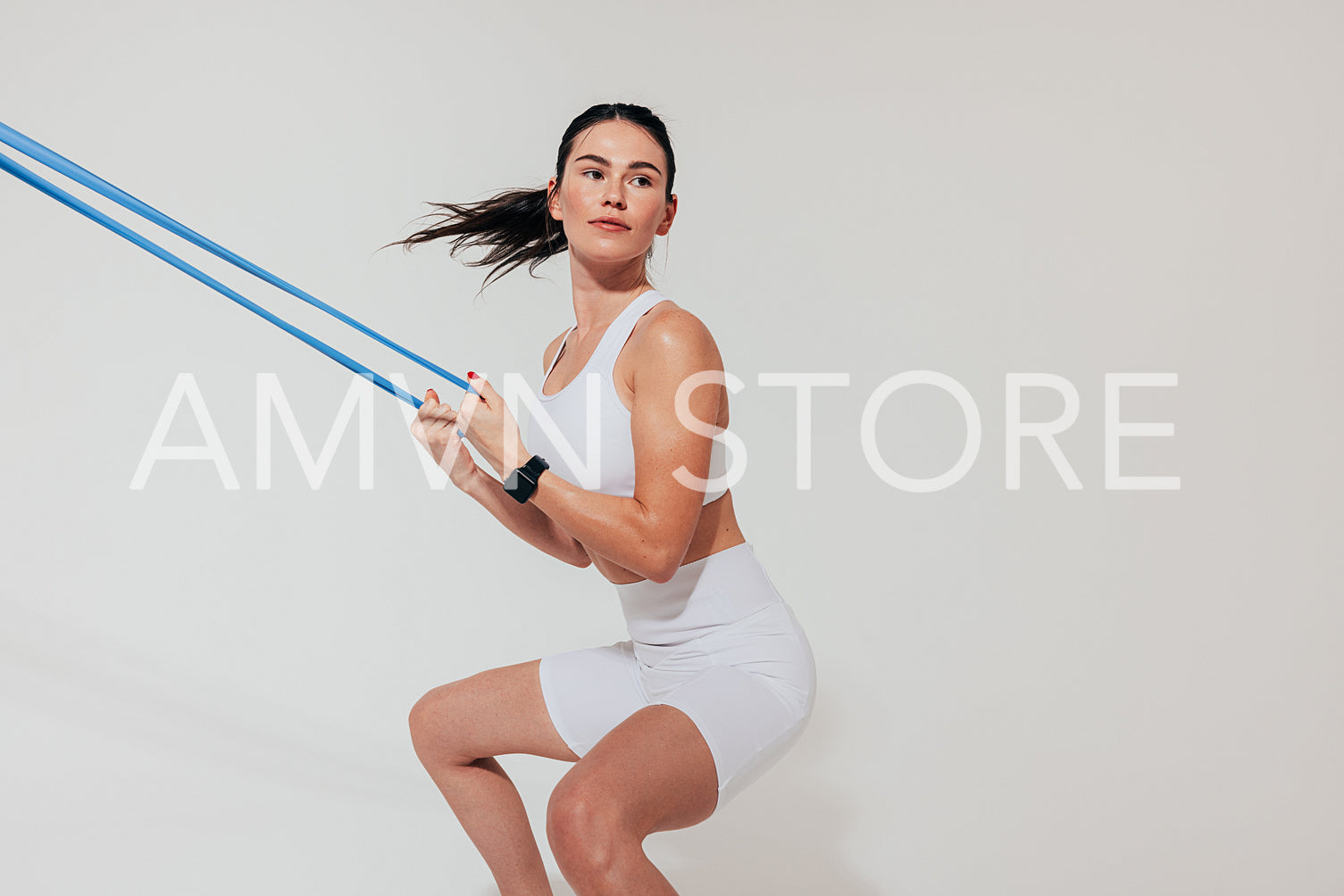 Young woman practicing squats over white background using a resistance band