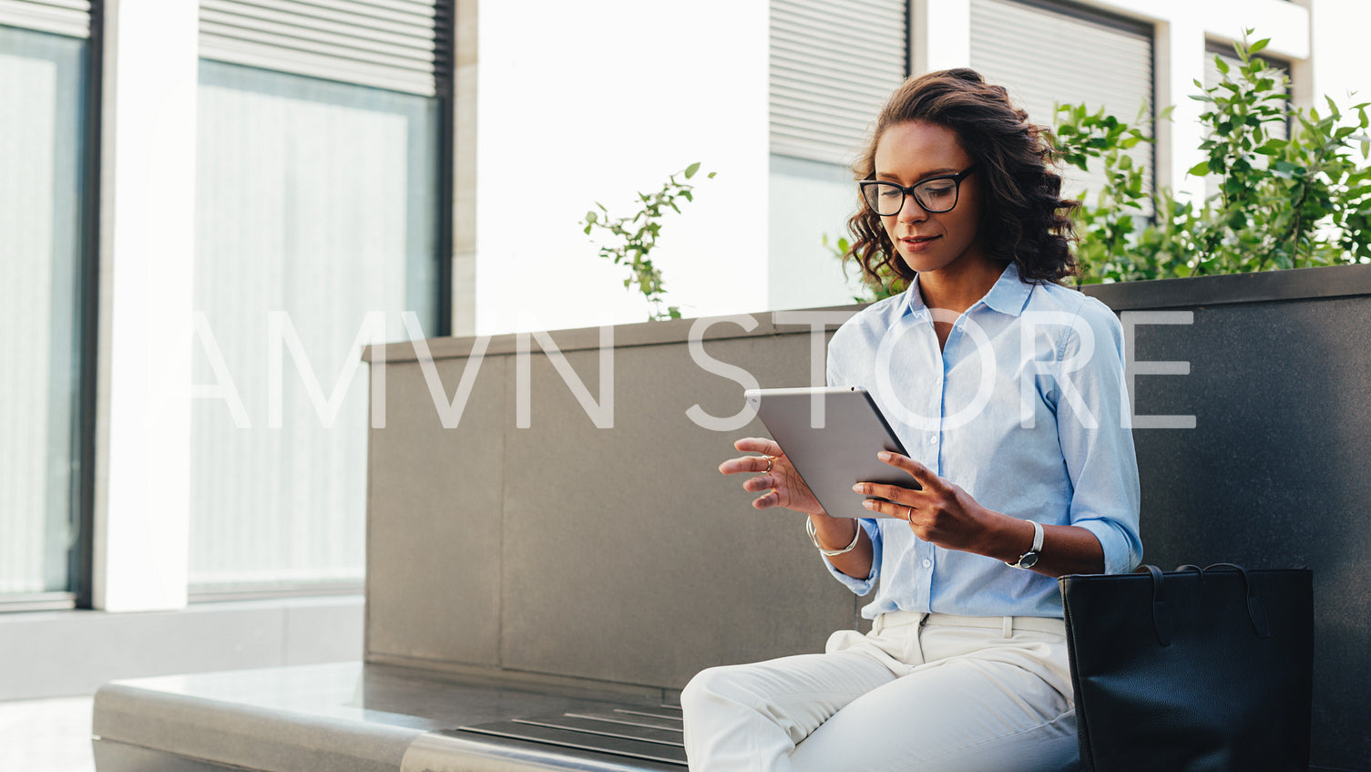 Woman sitting at office building and reading from digital tablet	