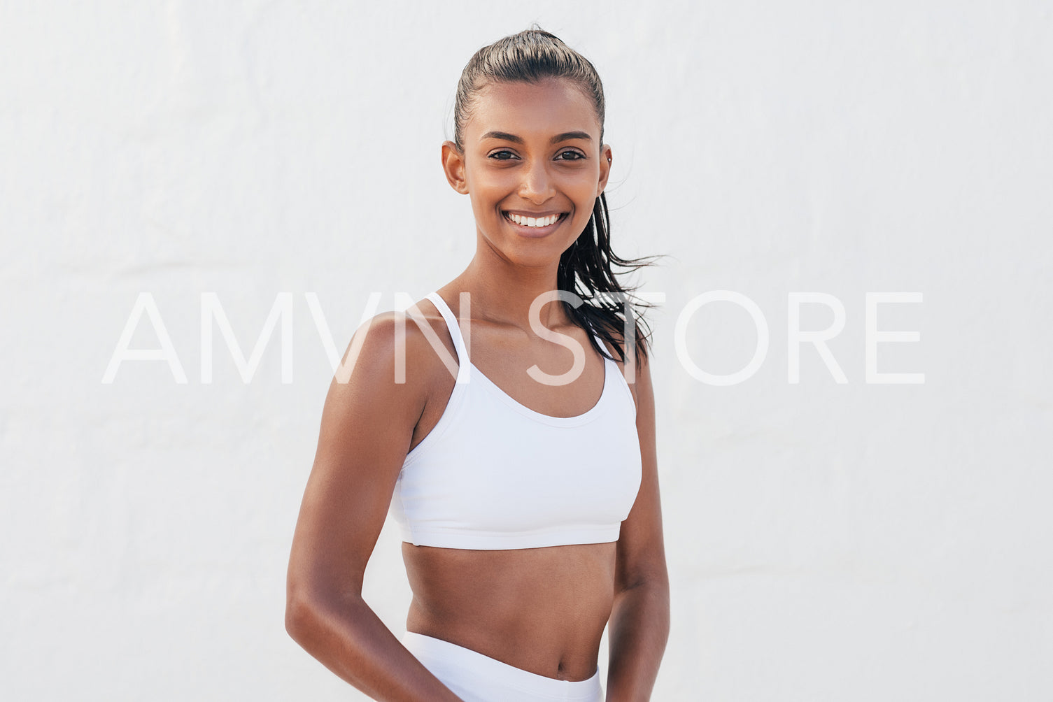 Portrait of a young slim female in fitness attire. Beautiful woman standing in an outdoor studio.