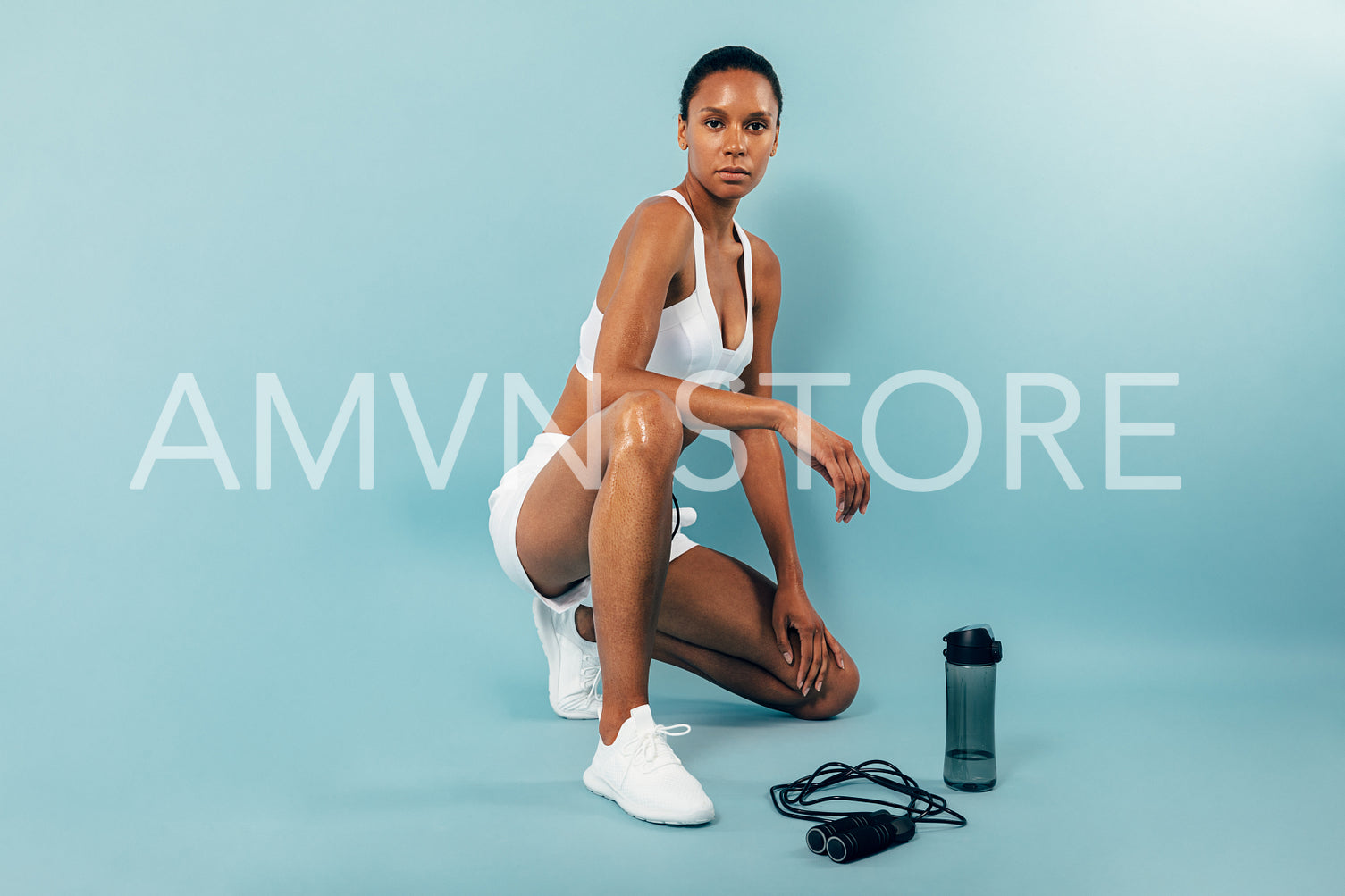 Young woman resting after working out with on blue background looking at camera	