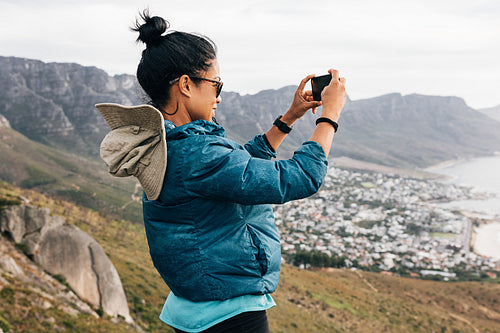 Woman tourist making photographs on mobile phone while hiking