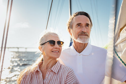 Portrait of two senior people looking away. Mature couple standing on yacht enjoying their sailing trip.