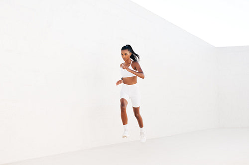 Fitness influencer runs fast outdoors in white studio