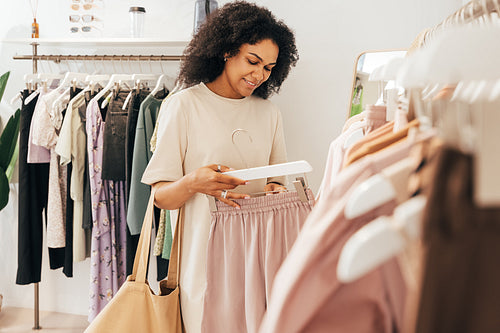 Woman looking at a quality of shorts in a clothing store. Shopper buying clothes in a boutique.