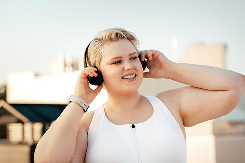 Plus size woman listening to music on the roof during training