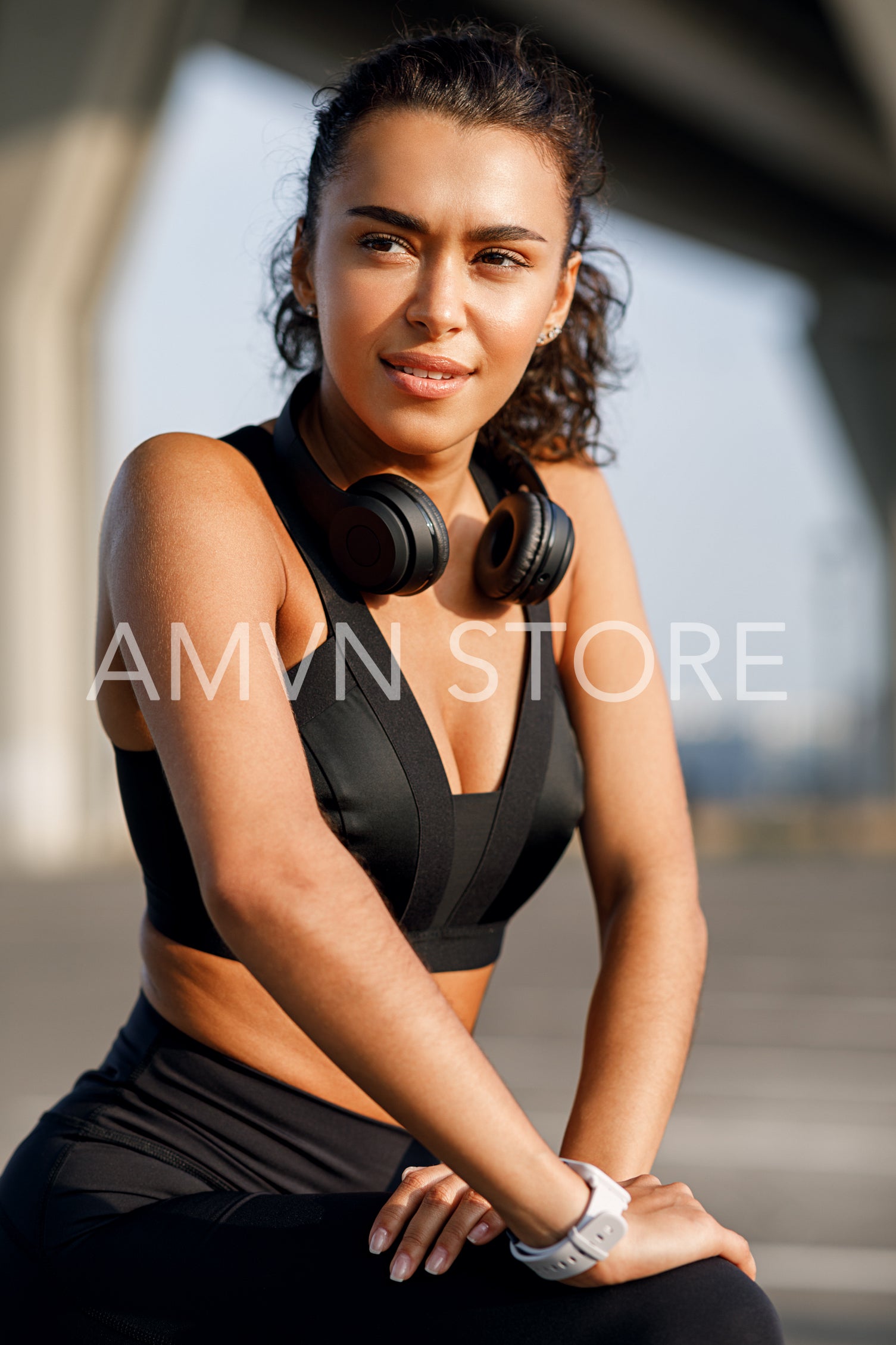 Healthy female athlete stretching legs outdoors. Beautiful sportswoman exercising at an evening under highway.	