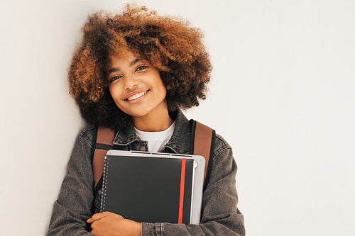 Beautiful girl with laptop and notebooks leaning wall in college. Portrait of a young woman in school.