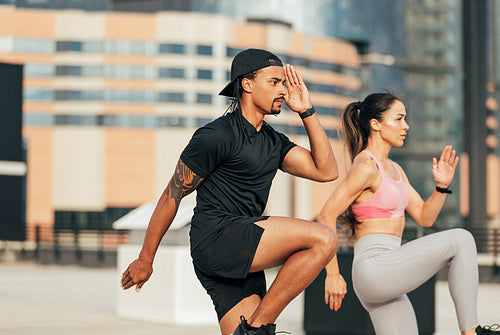 Fitness couple jumping together. Two athletes are warming up on a rooftop.