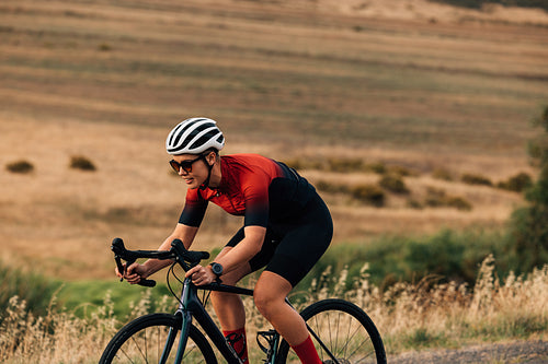 Sportswoman riding a bicycle on a country road. Professional cyclist practicing outdoors.