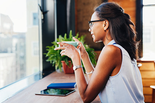 Side view of smiling female having coffee while working in cafe