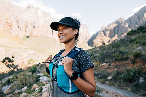 Cheerful woman in hiking attire standing outdoors looking on mountains