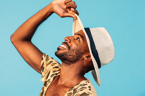 Happy African American man with straw hat looking up against blue background