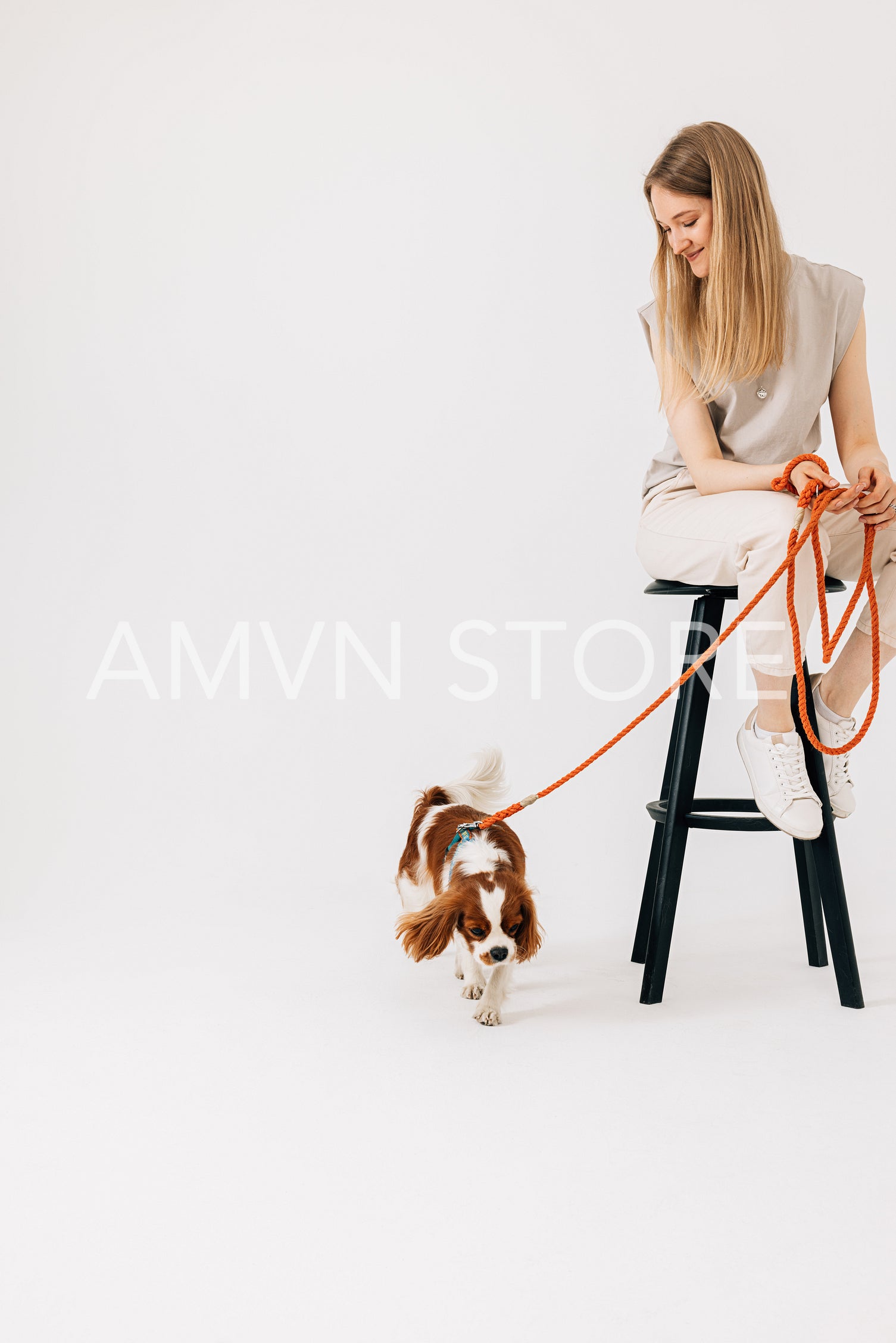 Young woman sitting on chair with dog leash and pet