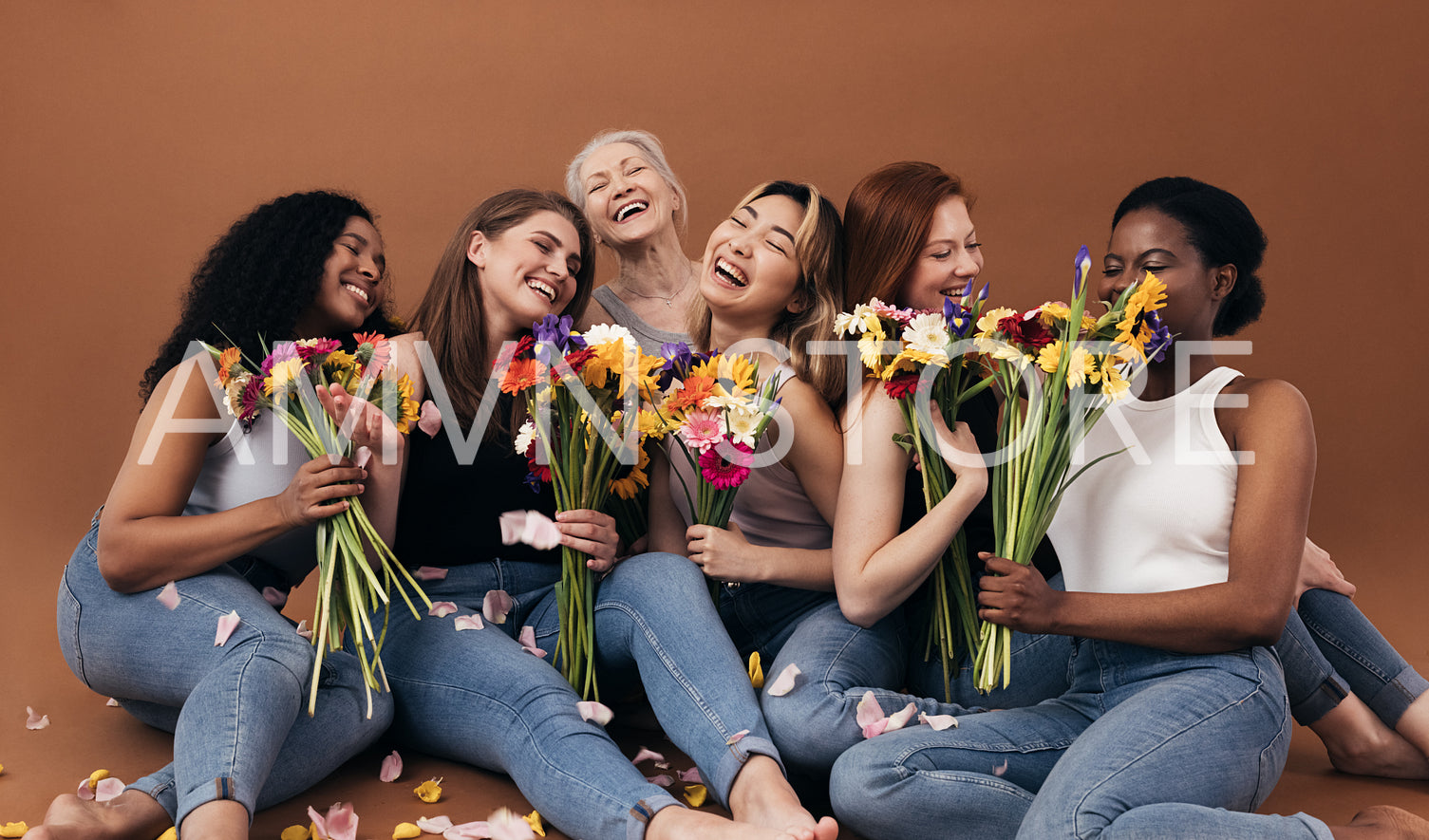 Six women of different ages and body types holding bouquets while sitting in studio against a brown background