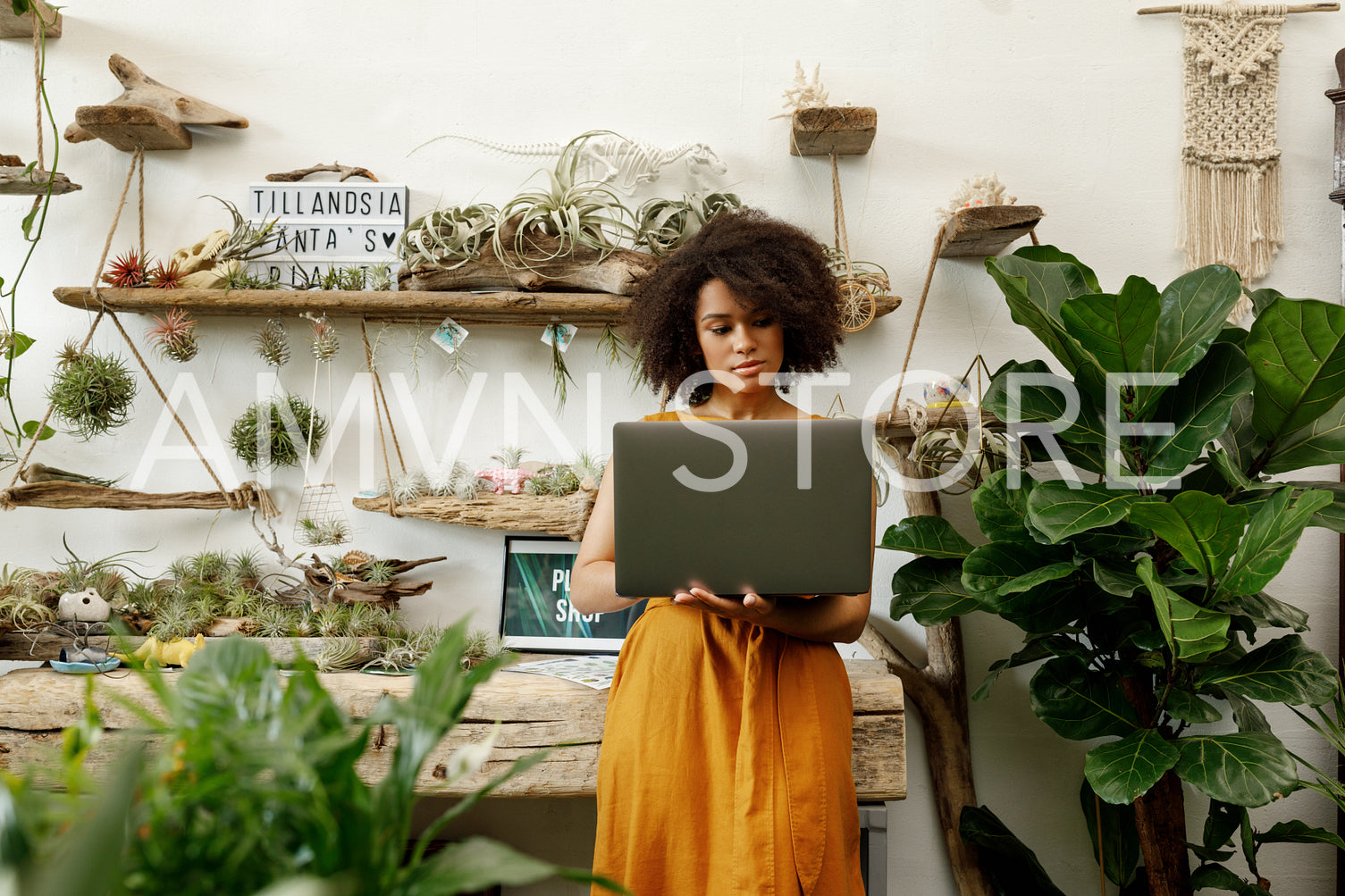 Young woman standing with laptop in her botanical studio	