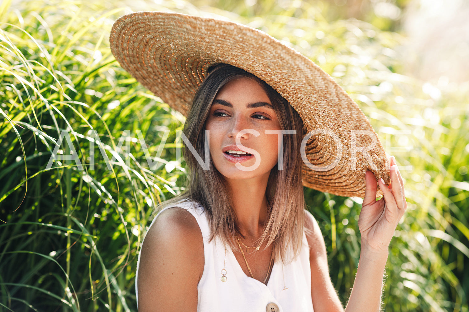 Portrait of a young woman in straw hat sitting in a park