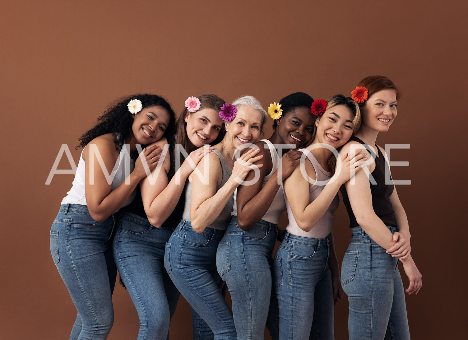 Group of six cheerful women with flowers in hair stand behind each other. Smiling females of different ages posing against a brown background.