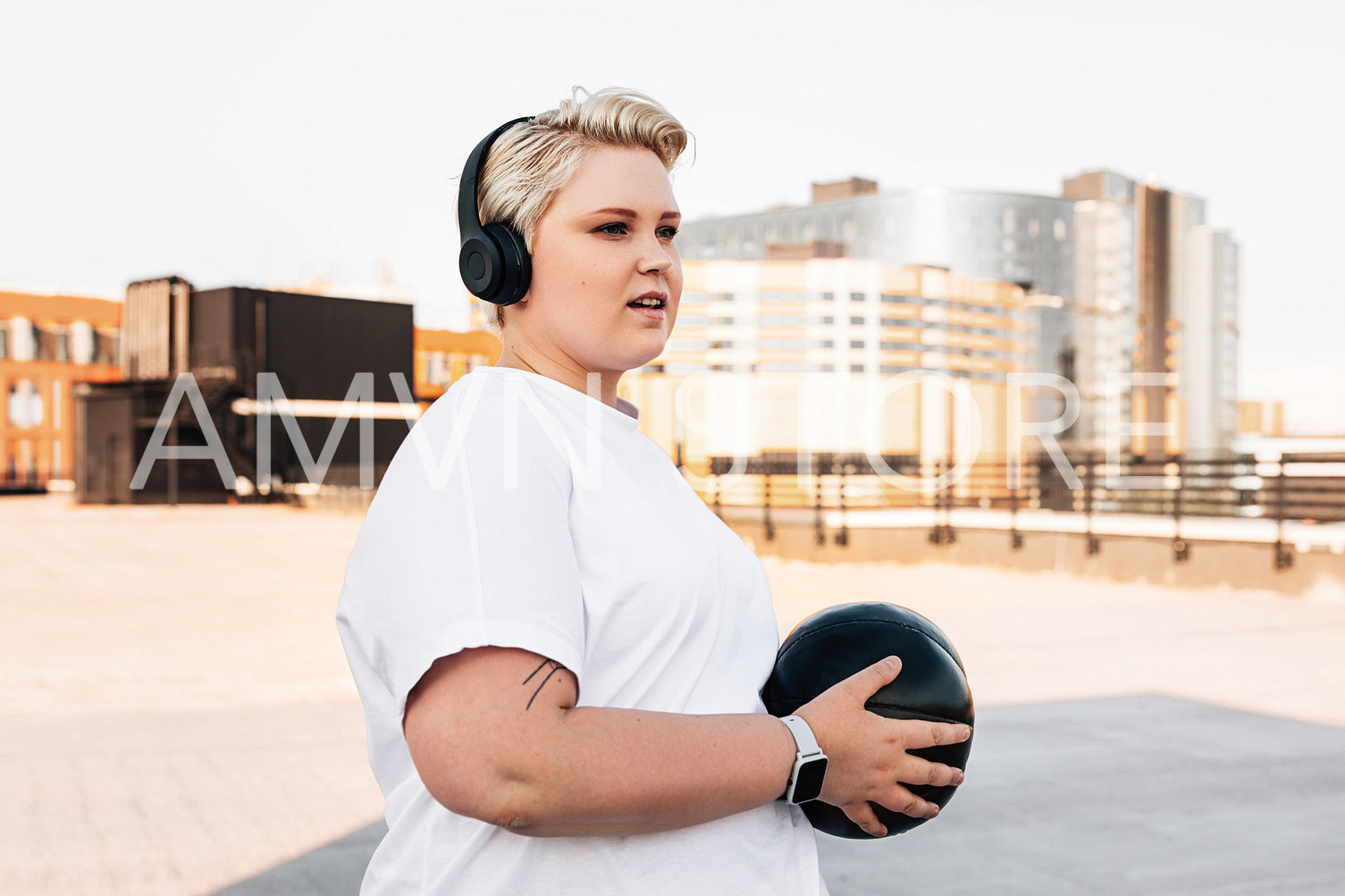 Young woman wearing headphones exercising with a medicine ball on the roof	