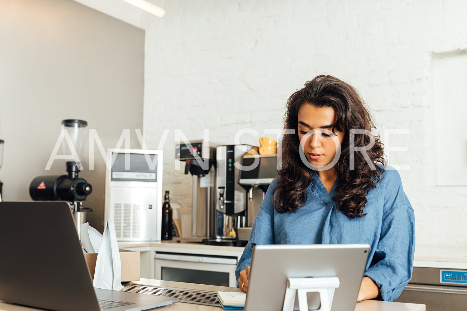 Confident cafe owner standing at table. Woman writing on documents in her coffee shop.	