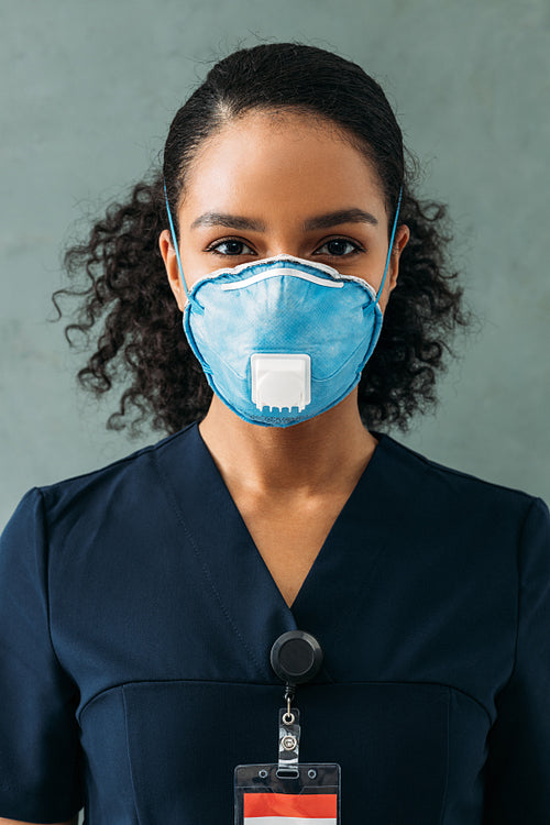 Close up portrait of a female nurse wearing a respirator and looking at the camera