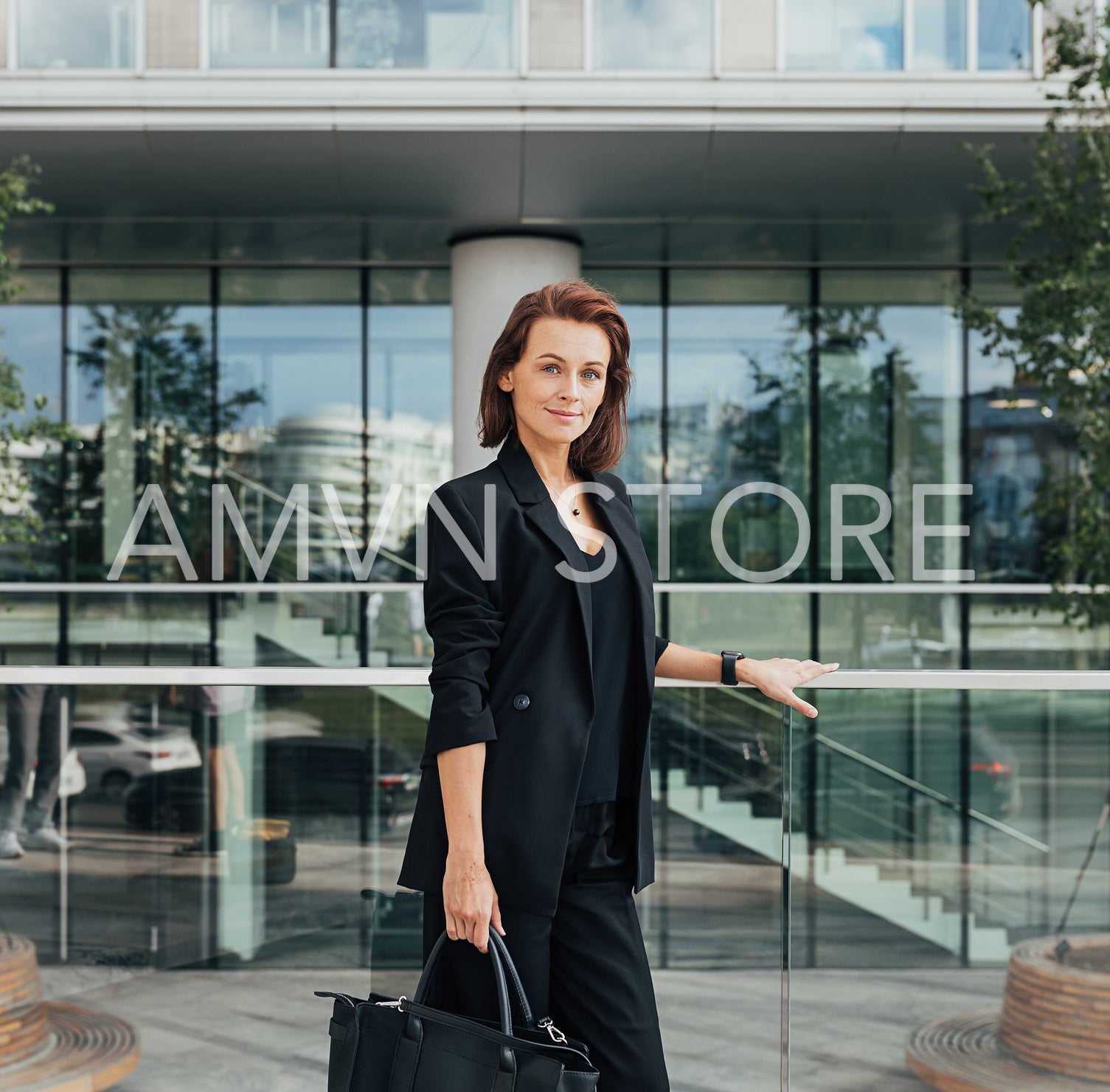 Portrait of a confident middle-aged female in formal wear with a bag against an office building