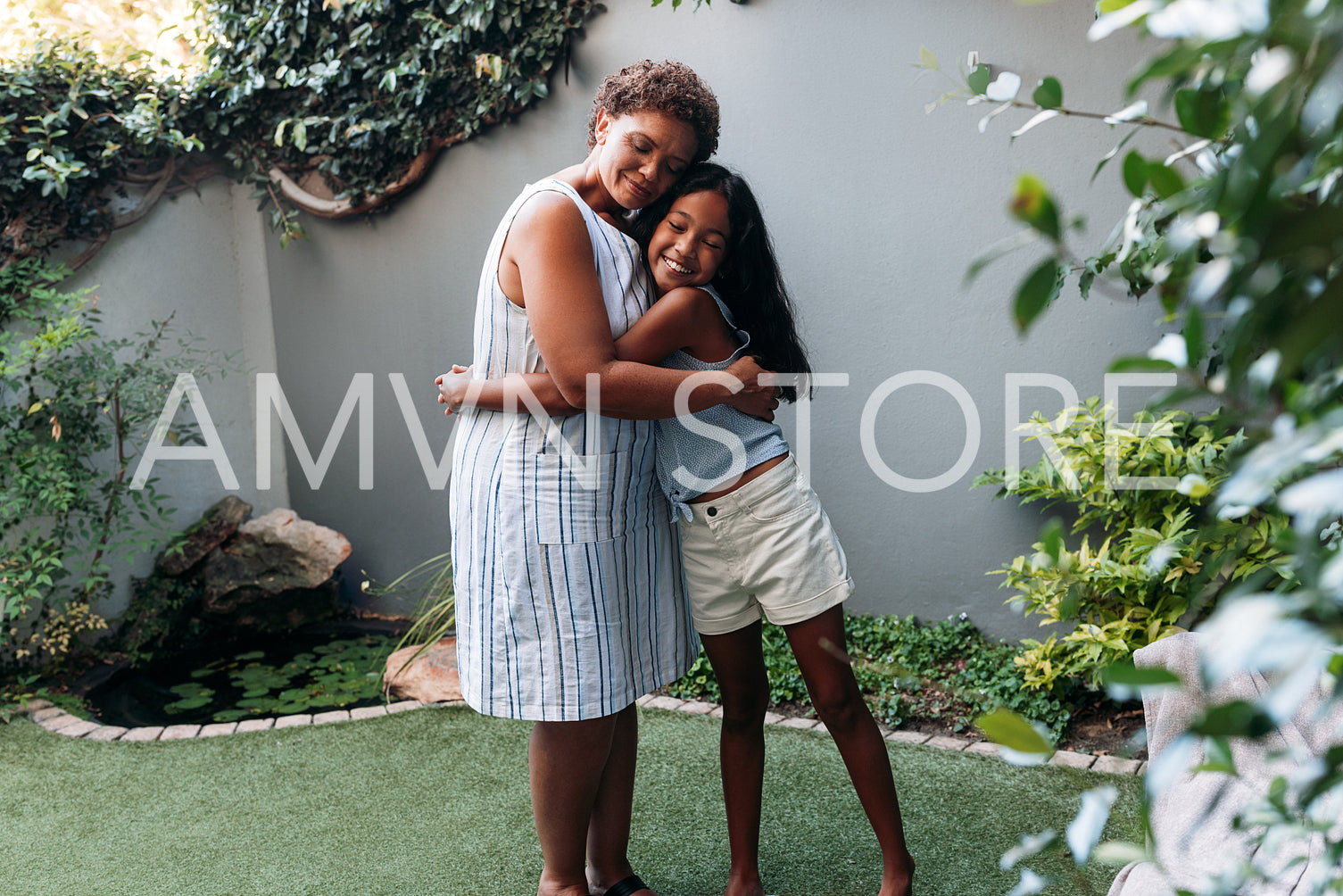 Granny and granddaughter embracing each other while standing in backyard