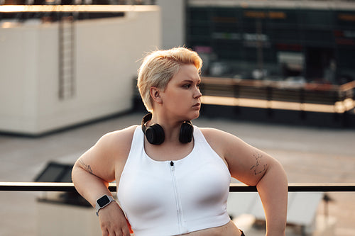 Side view of curvy woman with short hair leaning on a railing looking away