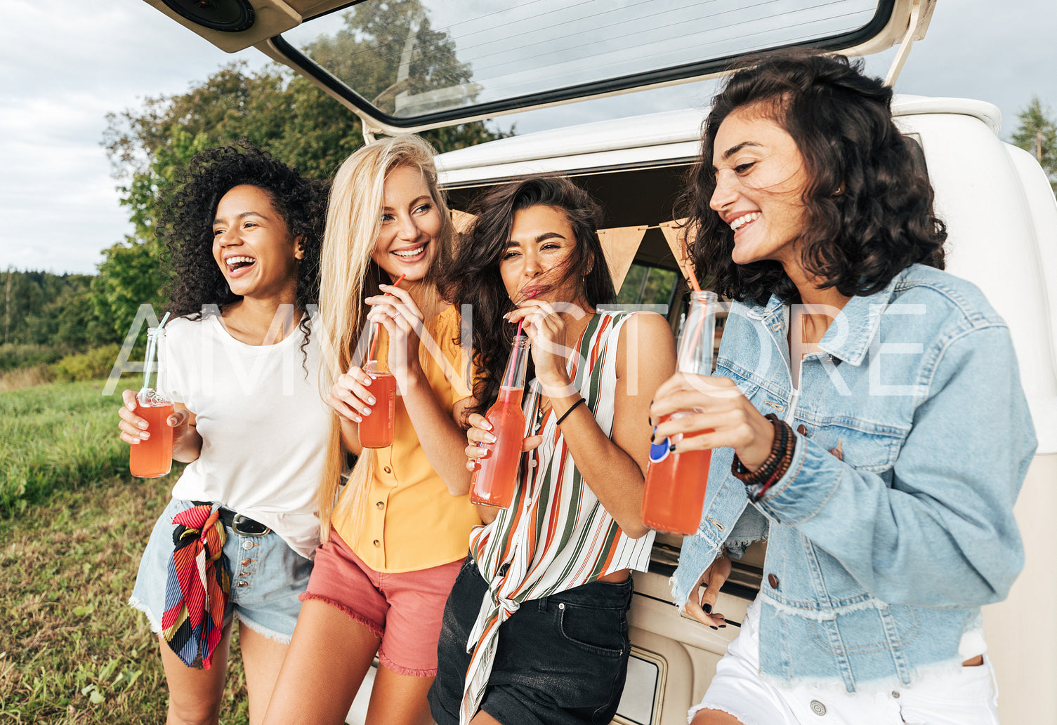 Group of four female friends celebrating during road trip standing at minivan