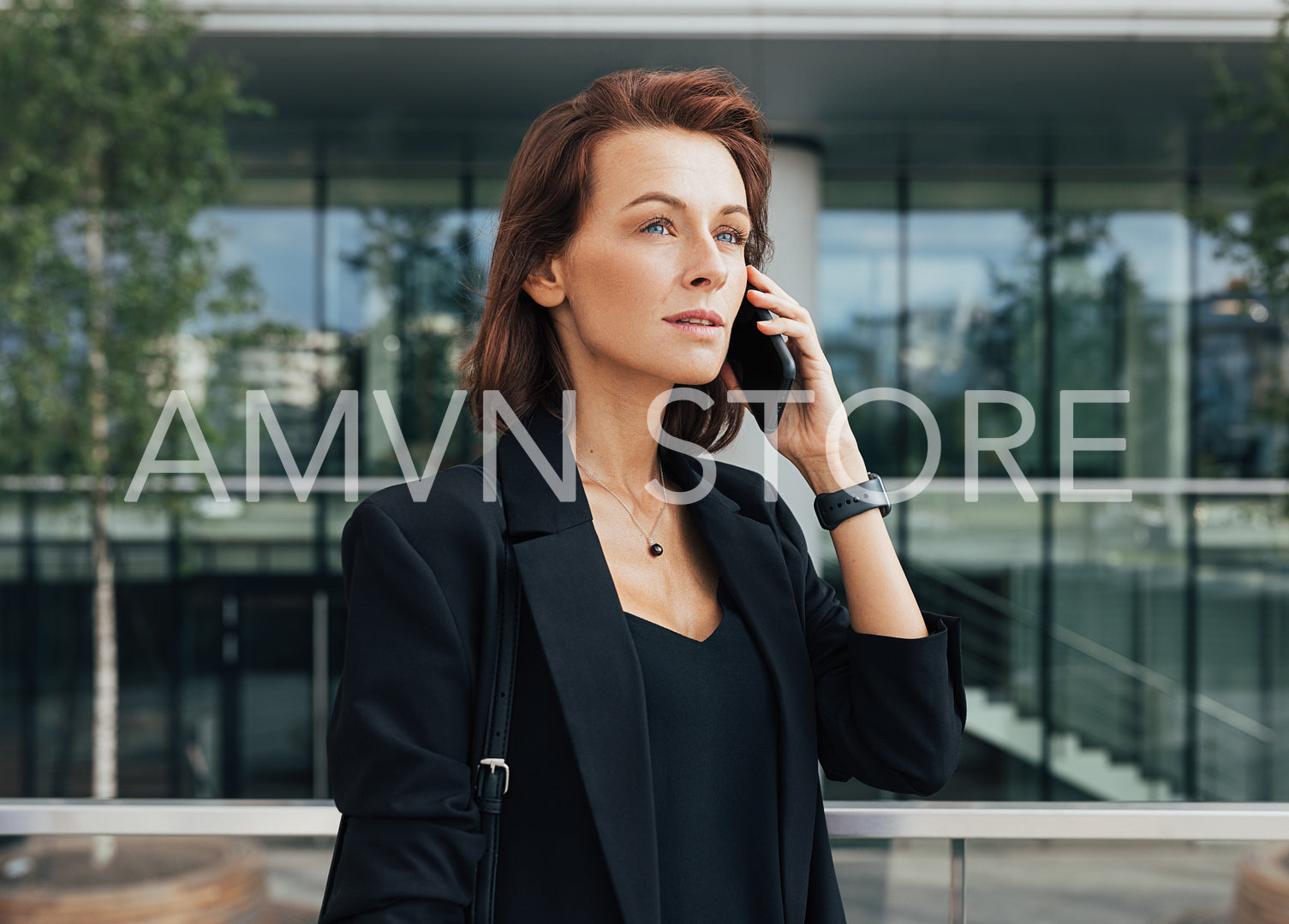 Side view of a beautiful businesswoman talking on a mobile phone against glass building