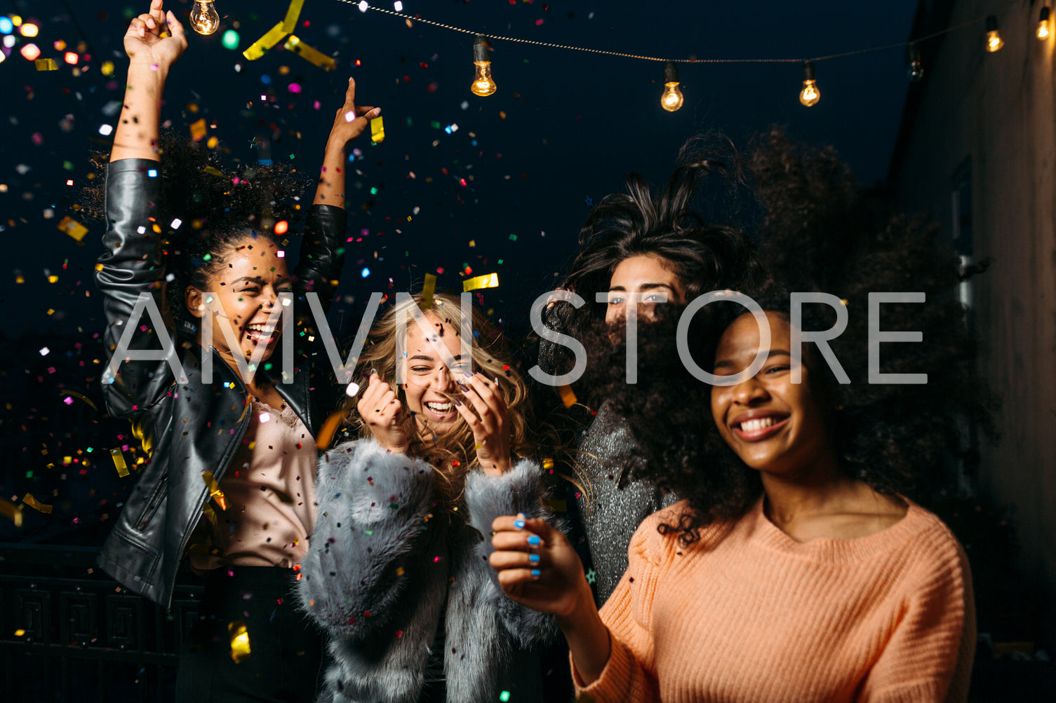 Group of female friends enjoying night party, throwing confetti	