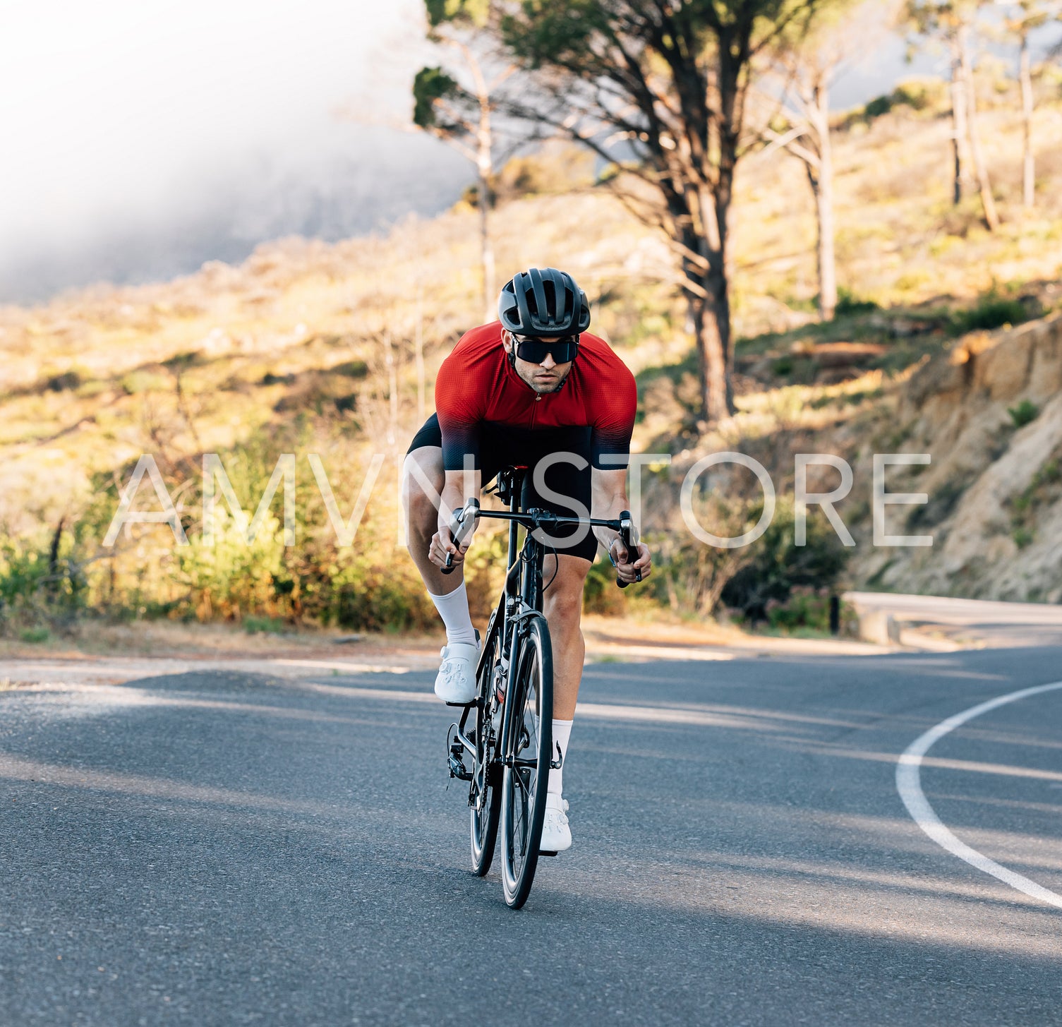 Young athlete riding a bicycle on an empty road. Cyclist in helmet and goggles exercising outdoors.