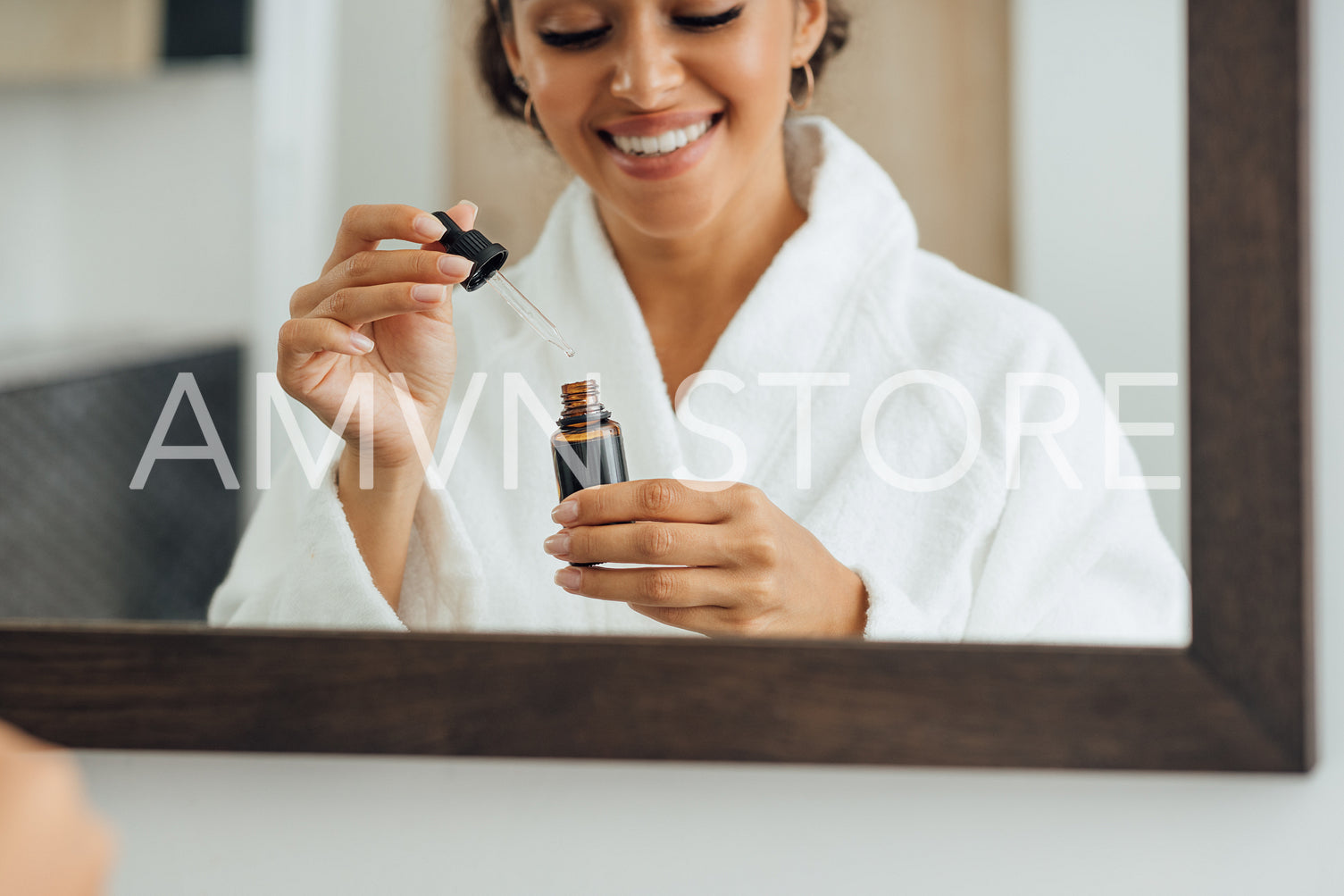 Close up of female hands holding a dropper and bottle with serum in bathrrom	