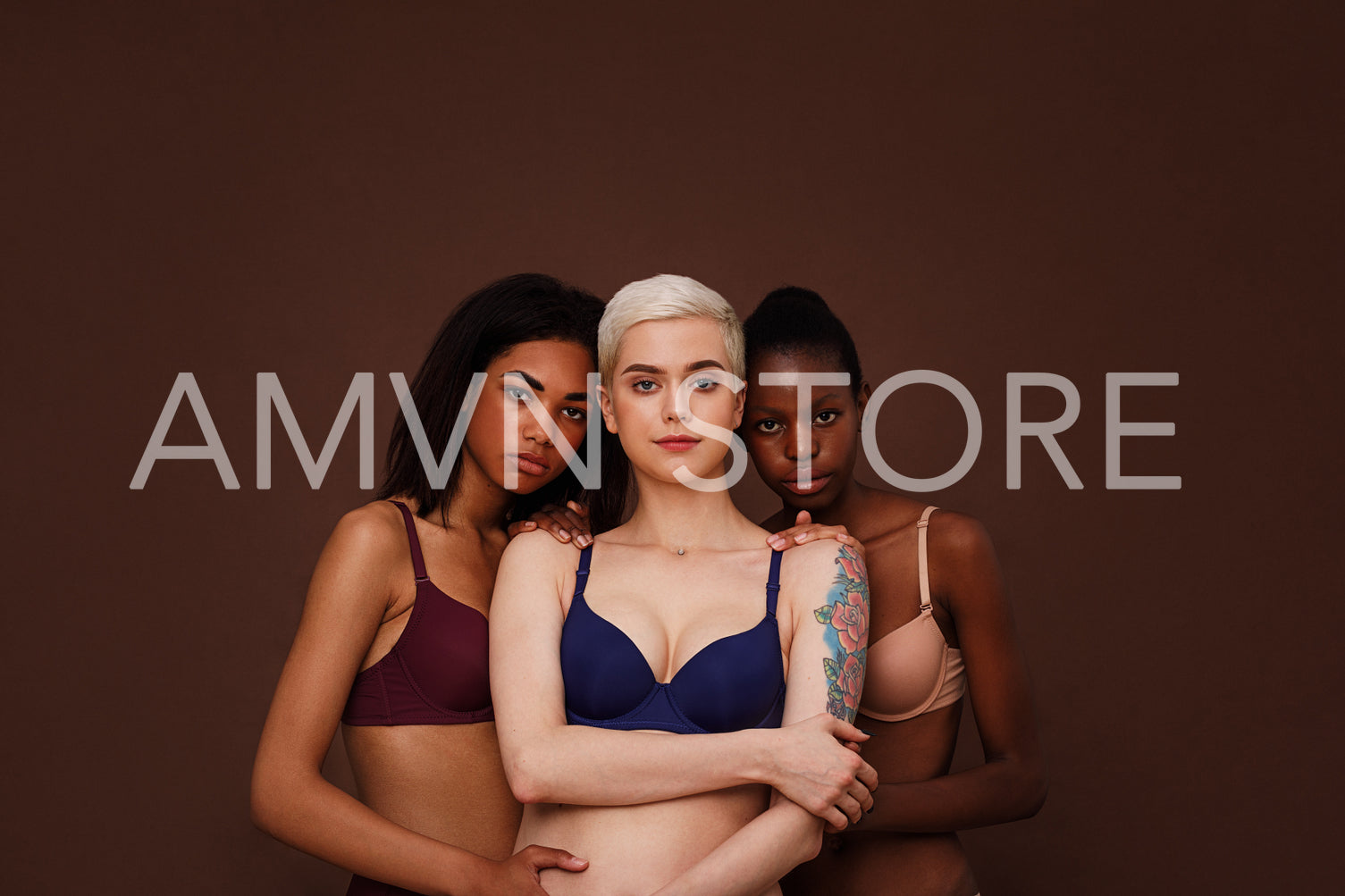 Three women of different skin color standing together. Group of young female in lingerie against backdrop.