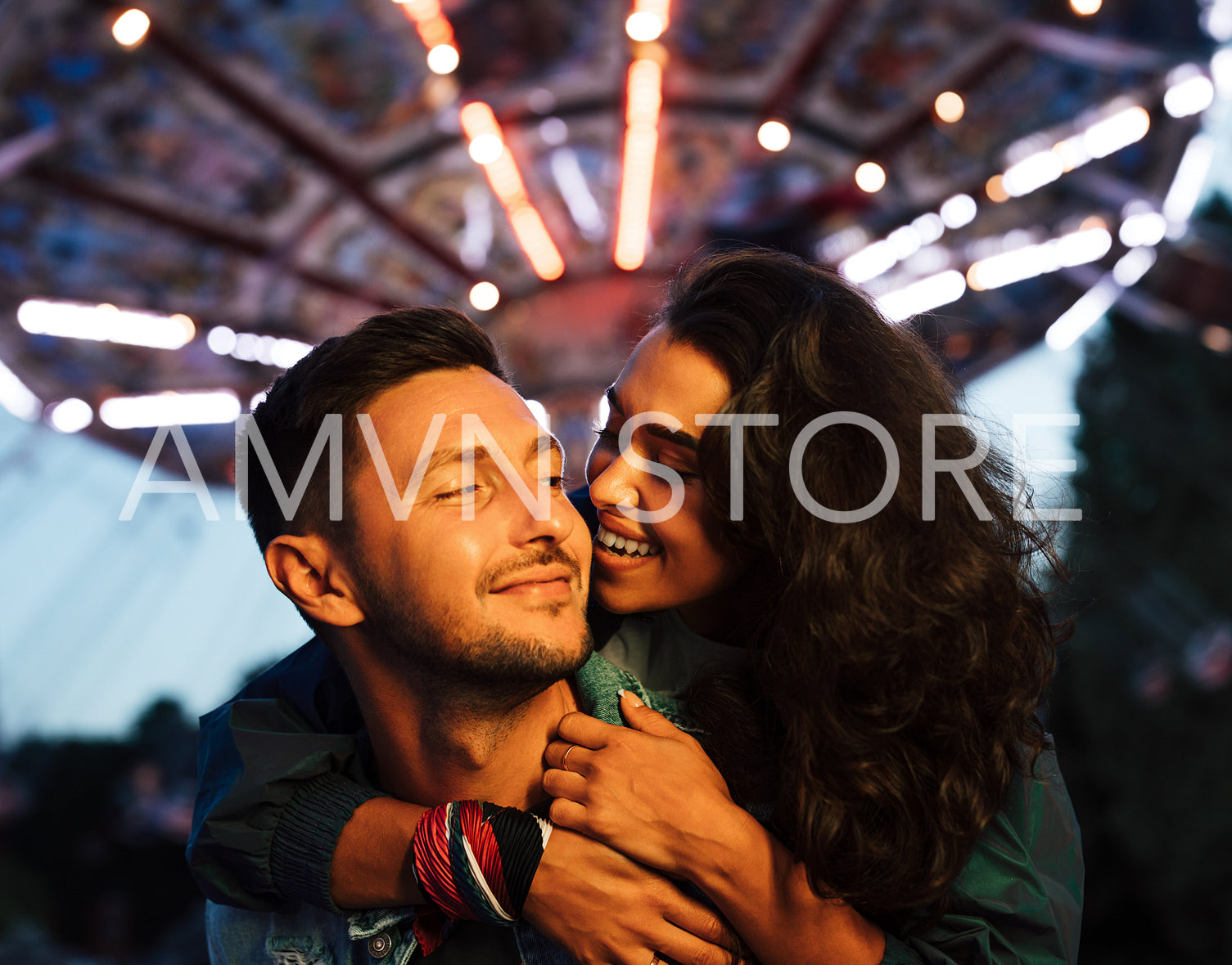 Young couple having fun ant night in amusement park