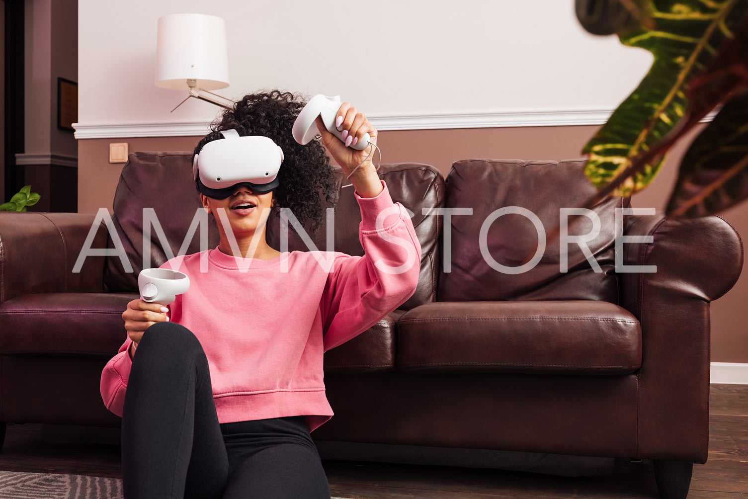 Woman with curly hair wearing VR helmet while sitting in living room at sofa