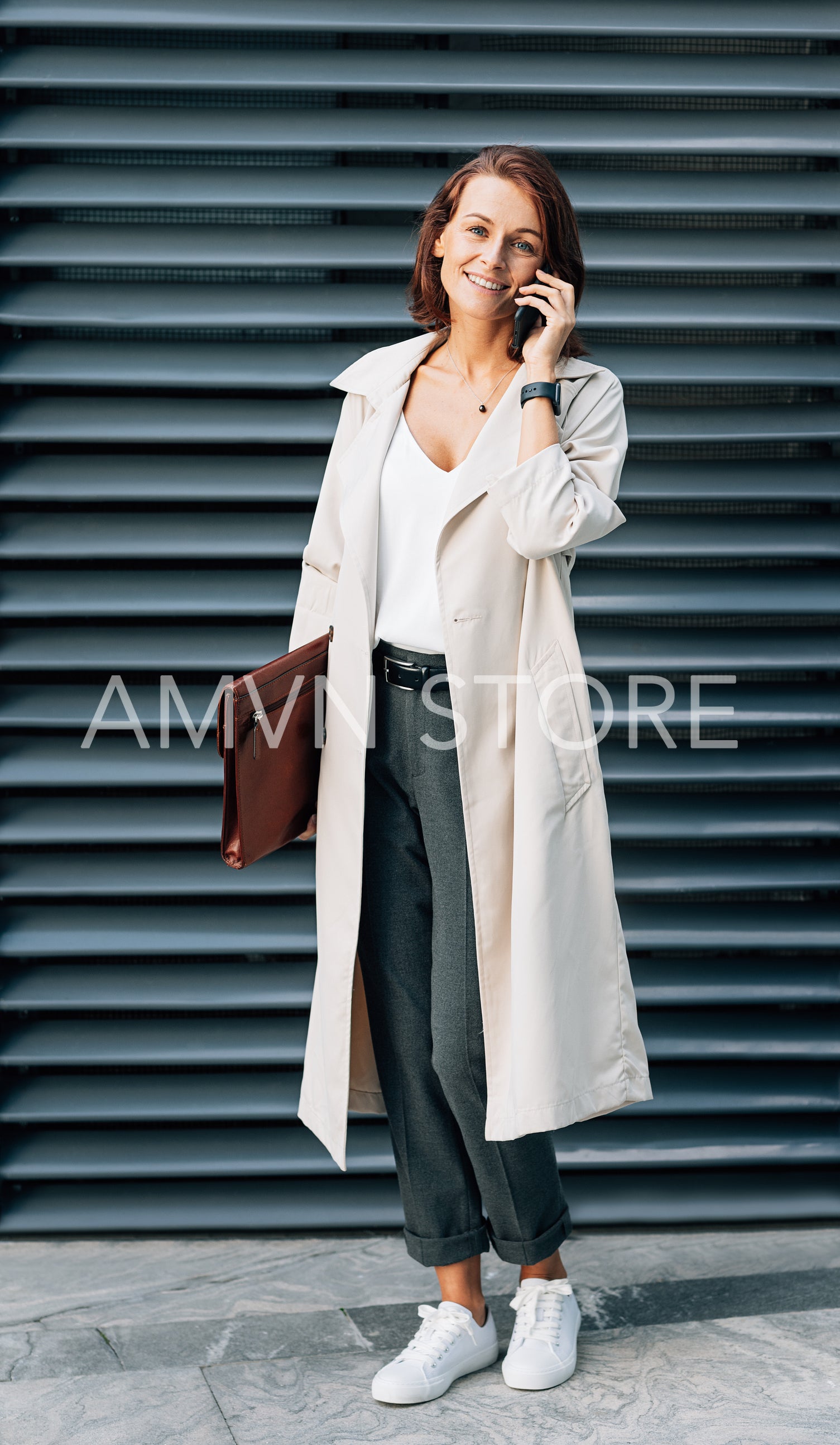 Stylish middle-aged woman wearing a coat talking on a mobile phone