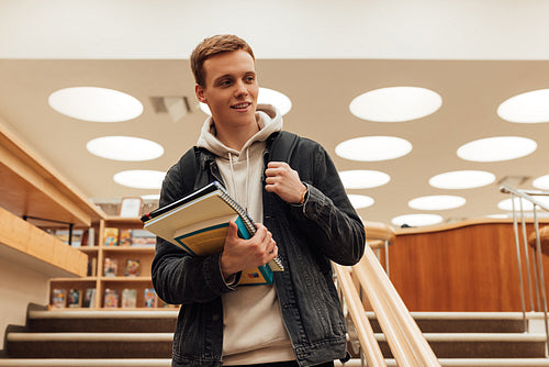 Teenager holding a books standing in college library