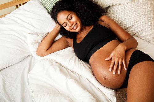 Young African American pregnant woman relaxing in bedroom