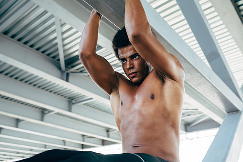 Sportsman doing abdominal exercise using bridge beam