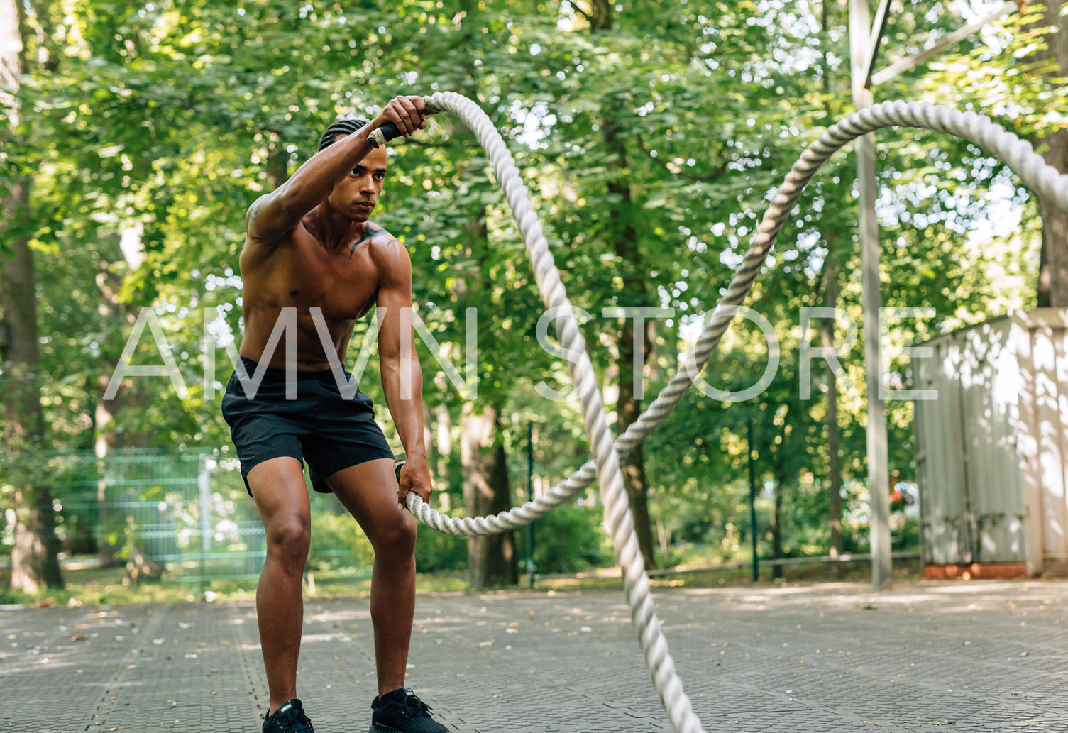 Side view of young man exercising with battling ropes outdoors	