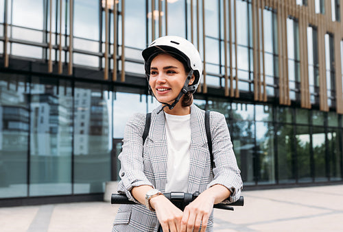 Beautiful smiling woman wearing cycling helmet looking away while standing in the city