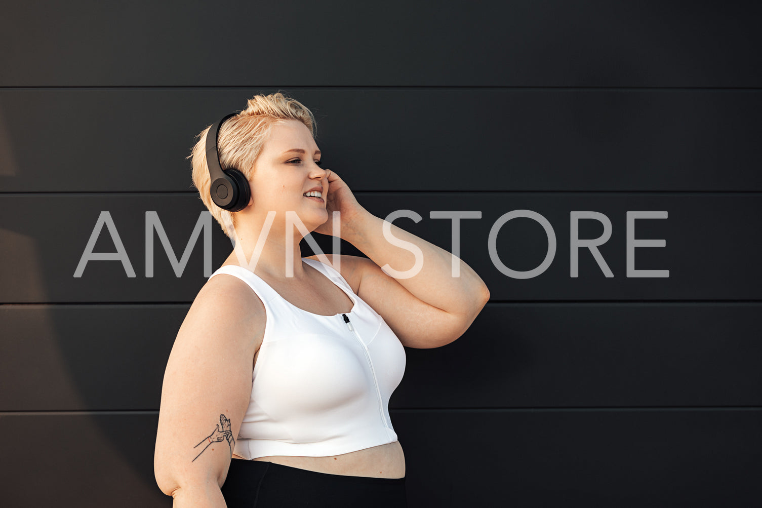 Side view of smiling woman in fitness clothes listening to music