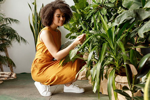 Young woman holding a book and observe a plant in workshop