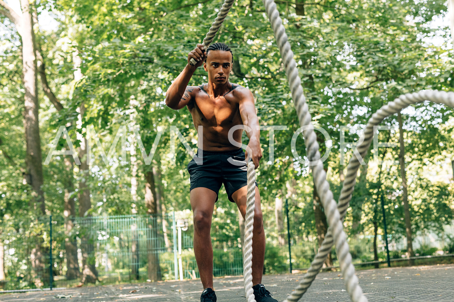 Man doing fitness workout with battling rope on sports ground	