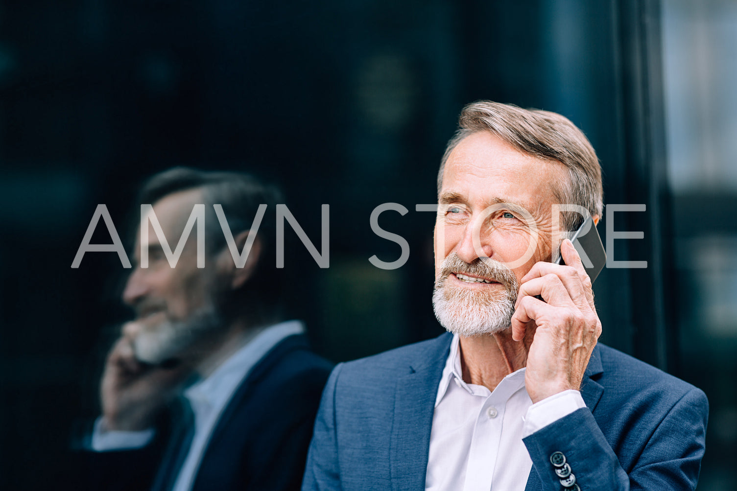 Senior businessman standing outdoors at office building and talking on cell phone	