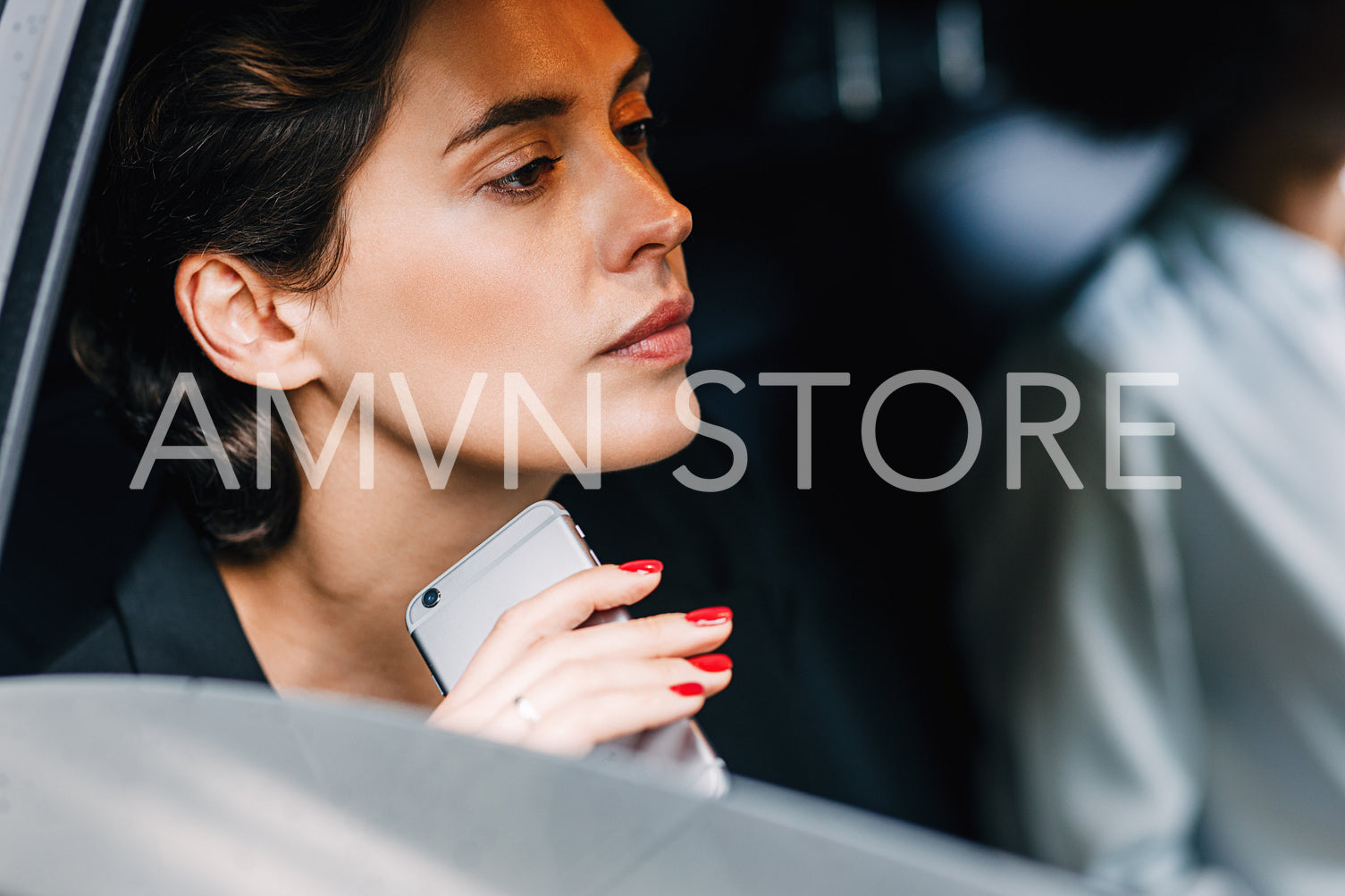 Pensive businesswoman holding a cell phone while sitting in a car	