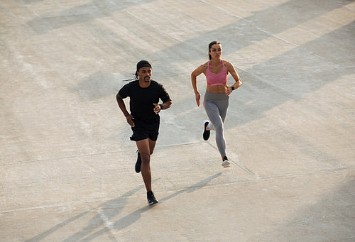 High angle of man and woman running together on rooftop at sunset