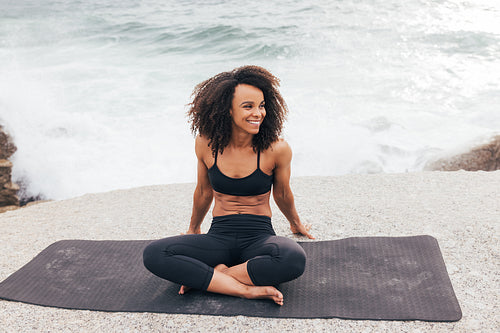 Happy female with curly hair relaxing on a mat during yoga