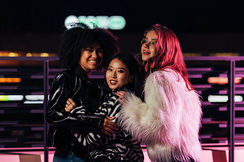 Smiling girls standing together outdoors at night and having fun