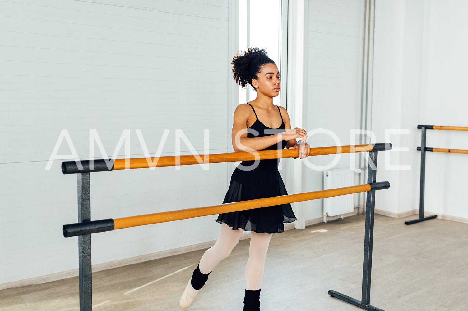 Woman in dancewear standing at ballet barre during training	